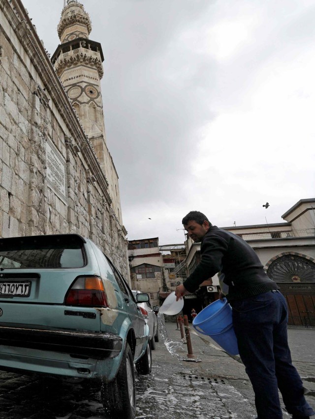 Warga Suriah mencuci mobil di tengah ancaman virus corona. Foto: REUTERS/Omar Sanadiki