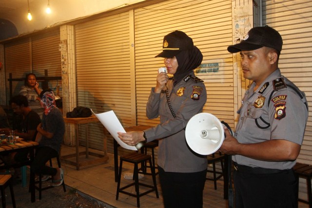 Polisi mengimbau kepada warga untuk membubarkan diri di sebuah kafe di Gorontalo, Senin (23/3). Foto: ANTARA FOTO/Adiwinata Solihin