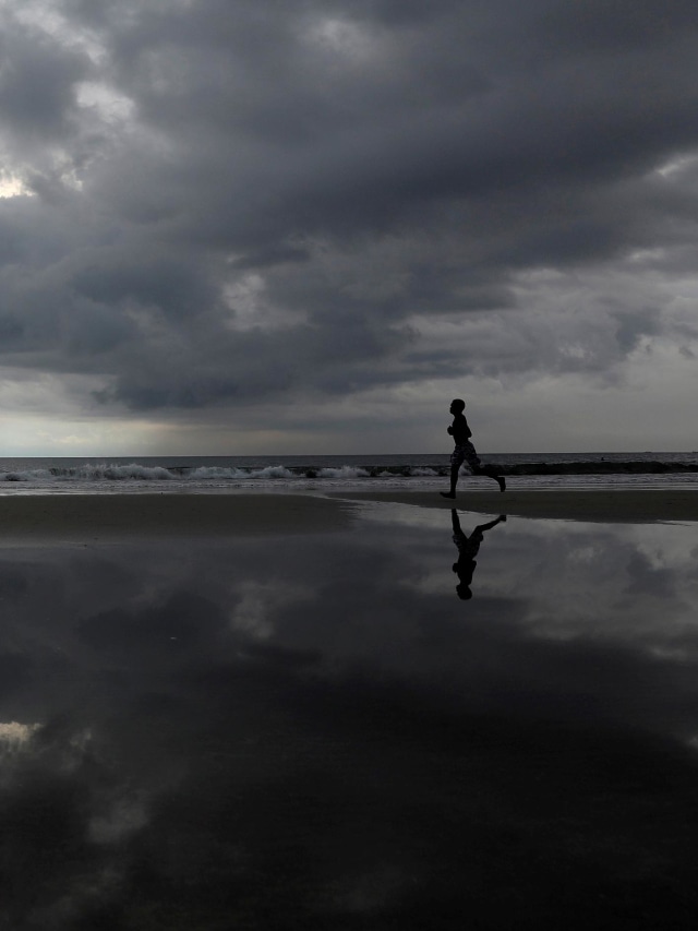 Seorang pria berlari di Pantai Kuta yang sepi, di tengah penyebaran penyakit virus corona (COVID-19) di Bali, Senin (23/3). Foto: REUTERS/Nyimas Laula