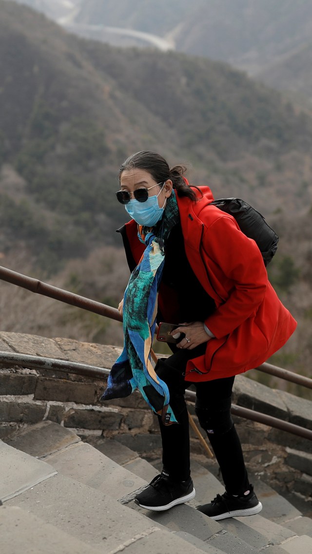 Sejumlah turis mengenakan masker saat mengunjungi Tembok Besar China di Badaling, Beijing, China, Selasa (24/3/2020). Foto: REUTERS/Thomas Peter