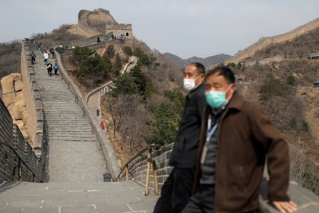 Sejumlah turis mengenakan masker saat mengunjungi Tembok Besar China di Badaling, Beijing, China, Selasa (24/3/2020). Foto: REUTERS/Thomas Peter