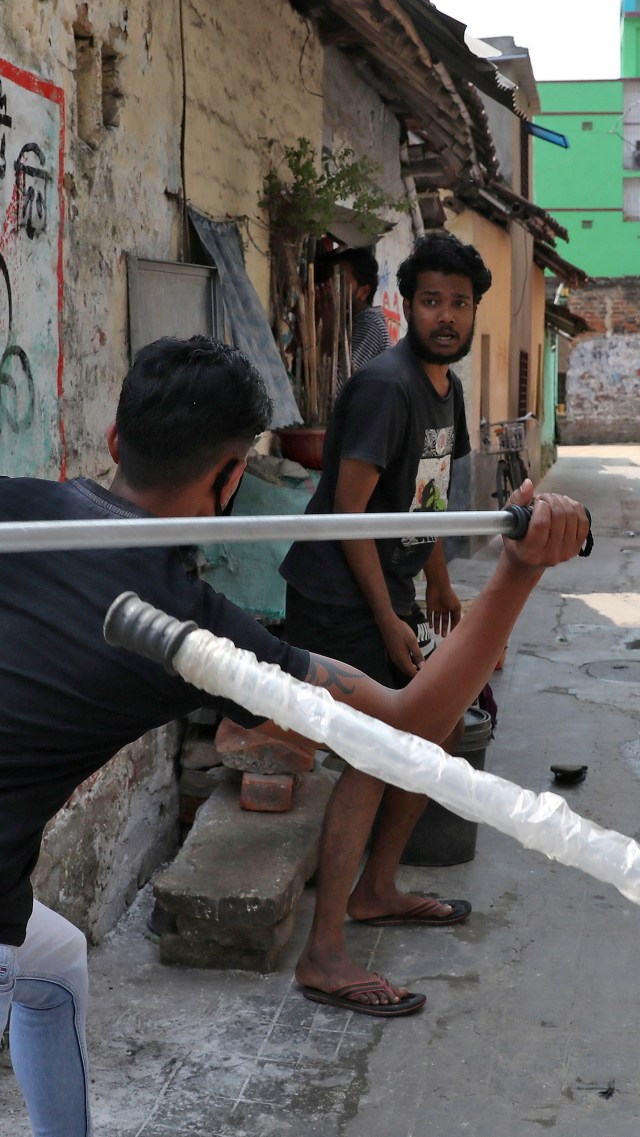 Seorang polisi berpakaian sipil menggunakan tongkatnya terhadap seorang pria sebagai hukuman karena melanggar aturan kuncian. Foto: REUTERS / Rupak De Chowdhuri