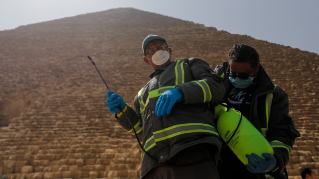 Petugas menyemprotkan cairan desinfektan di kawasan Piramida, Giza, Kairo, Mesir.  Foto: REUTERS / Amr Abdallah Dalsh