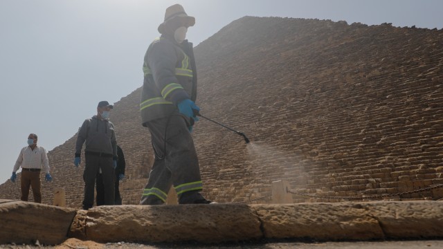 Petugas menyemprotkan cairan desinfektan di kawasan Piramida, Giza, Kairo, Mesir.  Foto: REUTERS / Amr Abdallah Dalsh