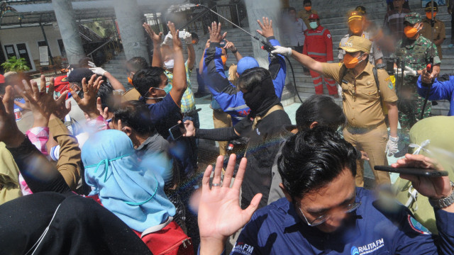 Bupati Pamekasan Badrut Taman (kedua kanan) menyemprotkan cairan disinfektan ke arah wartawan. Foto: ANTARA FOTO/Saiful Bahri