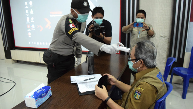 Petugas memeriksa suhu tubuh salah satu peserta rapat percepatan dan antisipasi dampak wabah virus corona atau COVID-19, di Aula Rupatama Polres Palu, Jumat (27/3). Foto: Humas Pemkot Palu