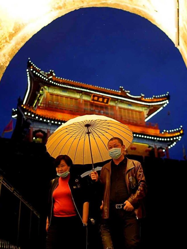 Warga menggunakan masker saat berjalan-jalan di Tembok  Kota Kuno di Jingzhou, Hubei. Foto: Reuters/Aly Song
