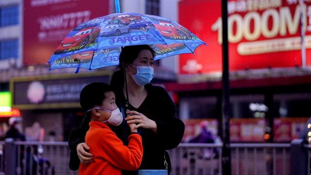 Anak bersama orang tua menggunakan masker di Jingzhou, Hubei. Foto: Reuters/Aly Song