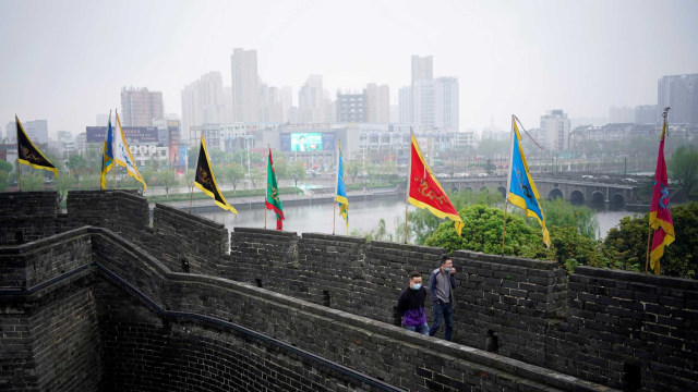 Warga  berjalan-jalan di tempat wisata Tembok Kota Kuno di Jingzhou, Hubei. Foto: Reuters/Aly Song