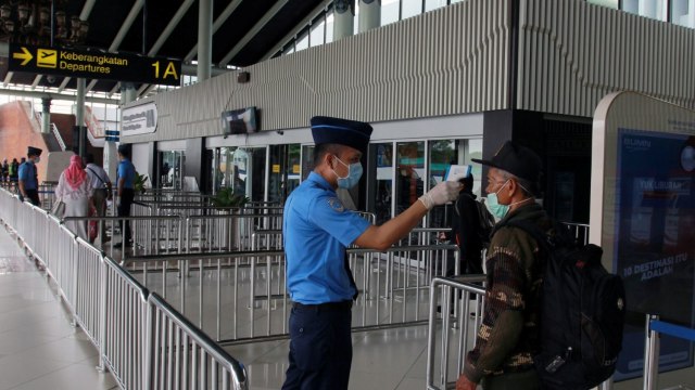 Petugas melakukan pengecekan suhu tubuh calon penumpang di Terminal 1 A Bandara Soekarno Hatta, Tangerang, Banten. Foto: ANTARA FOTO/Muhammad Iqbal