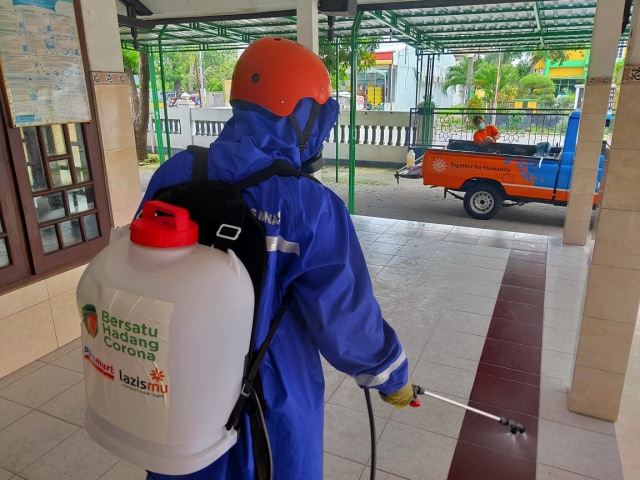 Salah seorang petugas menyemprotkan cairan desinfektan di fasilitas publik, Jumat (27/3/2020). Foto: Istimewa