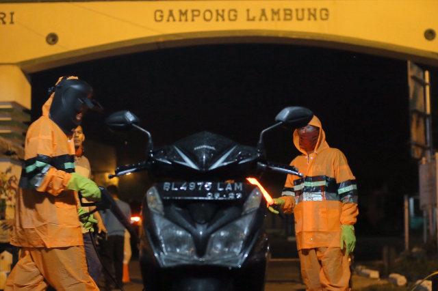 Warga Gampong Lambung, Banda Aceh menyemprot disinfektan setiap motor yang masuk. Foto: Abdul Hadi/acehkini