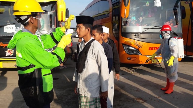 Para santri Jawa Timur sampai di Terminal Dukuh Salam Kabupaten Tegal dicek suhu tubuhnya. (foto: syaifullah)