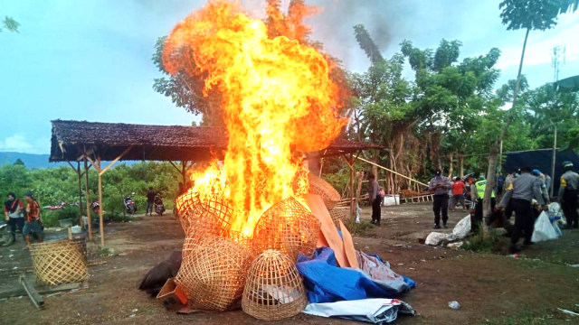 Petugas membakar puluhan sangkar, terpal, arena/jaring sabung ayam yang berada di lokasi arena sabung ayam di Kecamatan Tatanga, Kota Palu, Sulawesi Tengah, Minggu (29/3) sore. Foto: Dok. Polres Palu. 