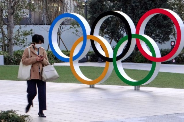 Ilustrasi warga yang melintas di depan logo olimpiade Tokyo. Olimpiade Tokyo 2020 dipastikan ditunda. Foto : Istimewa. 