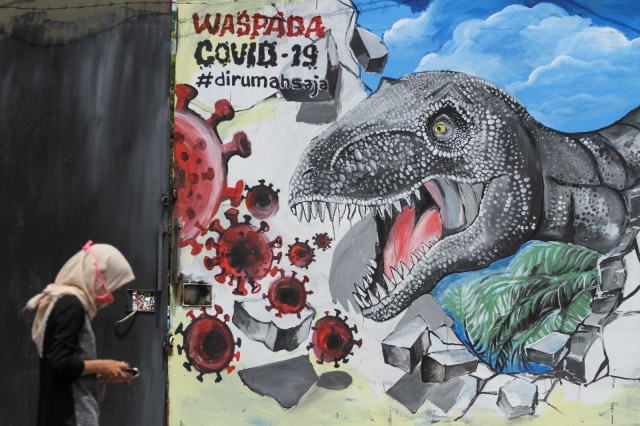 Seorang warga melintas di depan mural bertema COVID-19 di Jalan Baru, Depok, Jawa Barat, Senin (30/3). Foto: ANTARA FOTO/Asprilla Dwi Adha