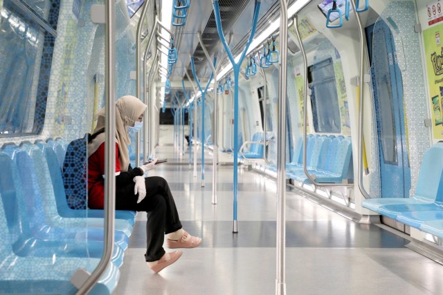 Seorang wanita mengenakan masker dan sarung tangan di dalam kereta Mass Rapid Transit, Kuala Lumpur, Malaysia. Foto: REUTERS / Lim Huey
