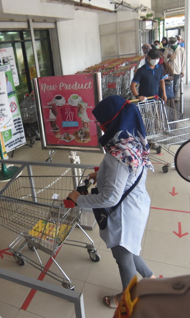 Warga antre berbelanja saat pemberlakuan pembatasan pengunjung supermarket di Tiptop, Depok, Jawa Barat, Senin (30/3/2020). Foto: ANTARA FOTO/Indrianto Eko Suwarso