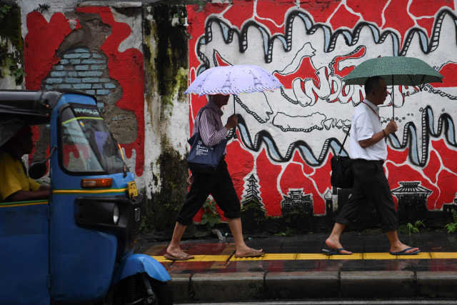 Warga menggunakan payung saat melintasi kawasan Tanah Abang, Jakarta. Foto: ANTARA FOTO/Wahyu Putro A