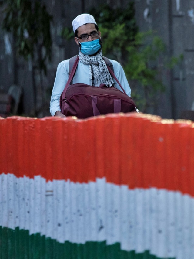 Seorang pria menggunakan masker berjalan menuju bus yang akan membawanya ke fasilitas karantina antisipasi virus corona di daerah Nizamuddin, New Delhi, India. Foto: REUTERS / Danish Siddiqui