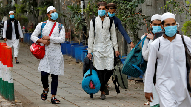 Sejumlahpria menggunakan masker berjalan menuju bus yang akan membawanya ke fasilitas karantina antisipasi virus corona di daerah Nizamuddin, New Delhi, India. Foto: REUTERS / Danish Siddiqui