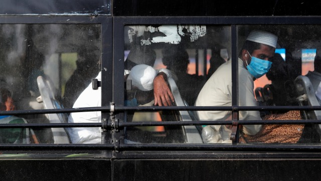 Sejumlah pria menggunakan masker di dalam bus yang akan membawanya ke fasilitas karantina antisipasi virus corona di daerah Nizamuddin, New Delhi, India. Foto: REUTERS / Danish Siddiqui