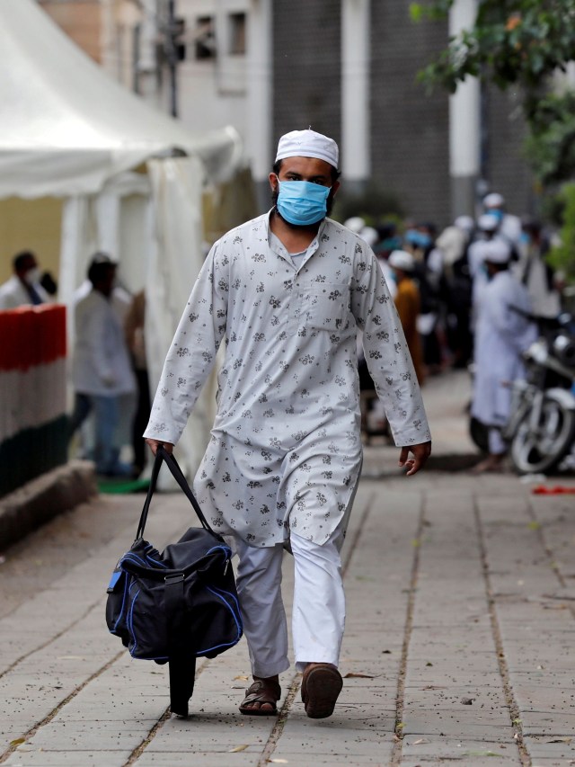Seorang pria menggunakan masker berjalan menuju bus yang akan membawanya ke fasilitas karantina antisipasi virus corona di daerah Nizamuddin, New Delhi, India. Foto: REUTERS / Danish Siddiqui