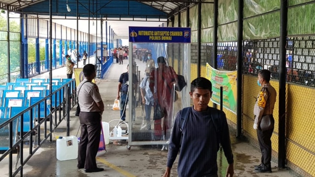 PARA penumpang dari Karimun, Kepulauan Riau, bergabung dengan ratusan TKI bekerja di Malaysia melewati bilik disinfektan usai turun dari feri RoRo Dumai, Riau.   