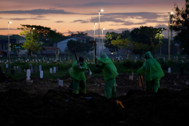 Sejumlah petugas memakamkan jenazah korban penyakit COVID-19 di Taman Pemakaman Umum (TPU), Jakarta, Selasa (31/3/). Foto: Reuters/Willy Kurniawan