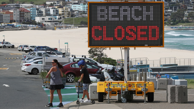 Warga berjalan di trotoar dekat Pantai Bondi yang ditutup di Sydney, Australia. Foto:  REUTERS / Loren Elliott
