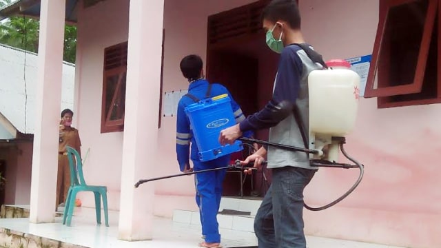 Perangkat Kampung Bawo melakukan penyemprotan cairan disinfektan di salah satu rumah warga untuk mencegah penyebaran virus corona