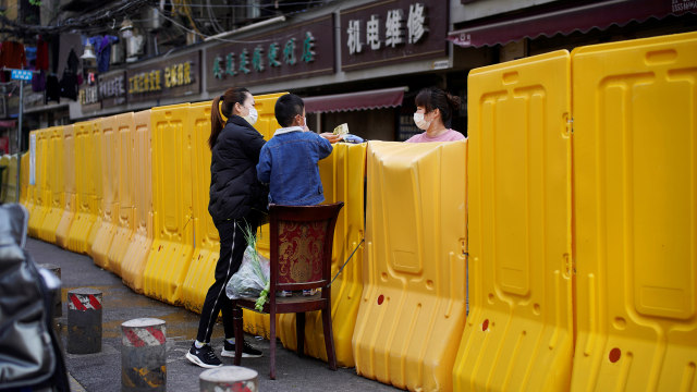 Sejumlah pembeli bahan makanan harus memanjat pagar yang mengelilingi pasar tradisional di Wuhan, Provinsi Hubei, China, Rabu (1/4/2020). Foto: Reuter/Aly Song