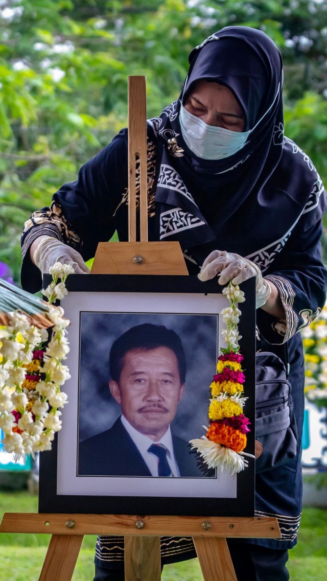 Kerabat mengalungkan bunga pada foto di pusara makam Bob Hasan saat prosesi pemakaman di Taman Makam Pahlawan Gatot Soebroto, Jawa Tengah, Rabu (1/4). Foto: ANTARA FOTO/Aji Styawan