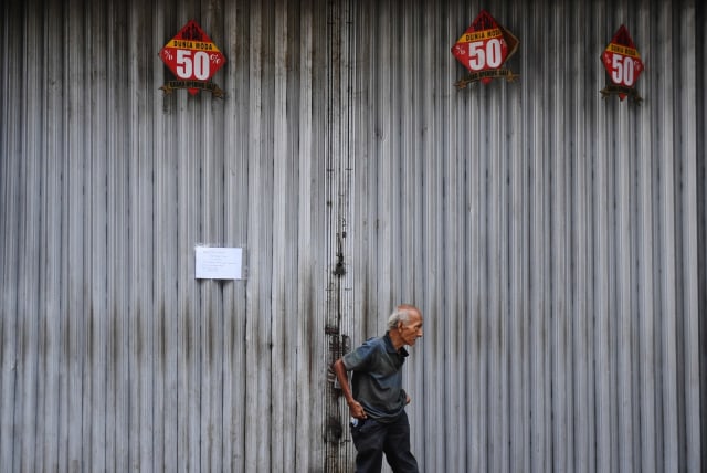 Seorang  pria melintasi deretan toko yang tutup di Pasar Baru, Jakarta, Rabu (1/4/2020).  Foto: ANTARA FOTO/Akbar Nugroho Gumay