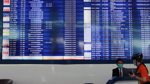 Petugas bandara berada dibawah Monitor jadwal penerbangan yang memperlihatkan pengumuman dibatalkannya penerbangan di Terminal 3 Bandara Soekarno Hatta. Foto: ANTARA FOTO/Muhammad Iqbal