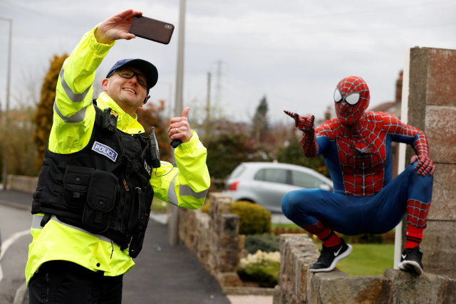 Spiderman berfoto dengan polisi di Stockport, Inggris saat lockdown. Foto: REUTERS/Phil Noble