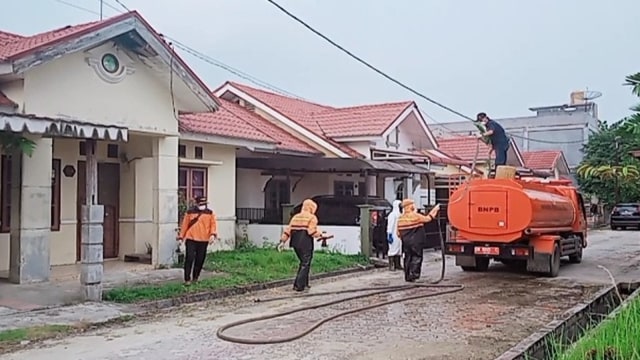 ANGGOTA BPBD Pelalawan, Riau, menyemprotkan cairan disinfektan di perumahan warga Pangkalan Kerinci positif Covid-19, Kamis, 2 April 2020. 
