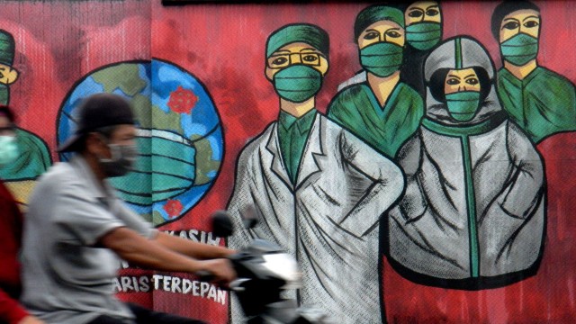 Pengendara motor melintas di depan mural tentang pandemi virus corona atau COVID-19 di Jalan Raya Jakarta-Bogor, Depok, Jawa Barat. Foto: ANTARA FOTO/Yulius Satria Wijaya
