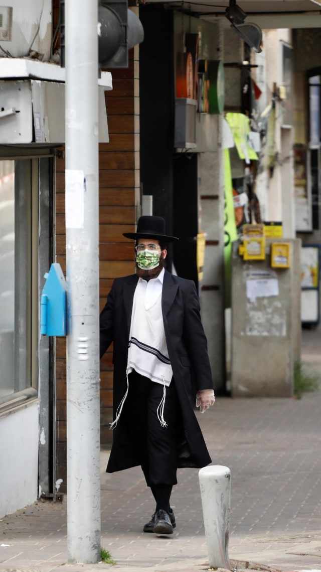 Seorang pria Yahudi ultra-Ortodoks berjalan kaki di tengah kota, selama lockdown di Israel. Foto: REUTERS/Ronen Zvulun