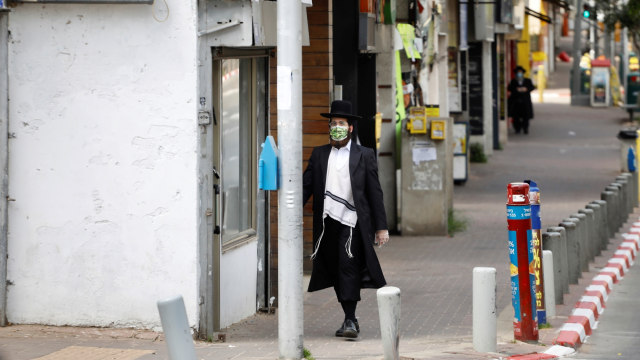 Seorang pria Yahudi ultra-Ortodoks berjalan kaki di tengah kota, selama lockdown di Israel. Foto: REUTERS/Ronen Zvulun