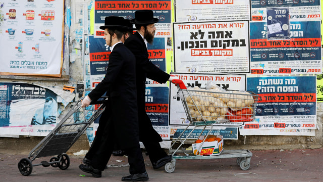 Sejumlah pria Yahudi ultra-Ortodoks mendorong troli belanjaan selama lockdown di Israel. Foto: REUTERS/Ronen Zvulun
