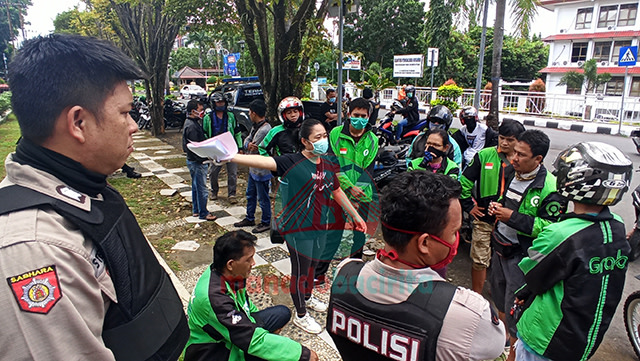 Kepolisian berjaga di pintu gerbang masuk kantor Pemerintah Provinsi Sulut untuk menertibkan Ojek Online (Ojol) yang membludak karena mengantri untuk mendapatkan bantuan sembako dari pemerintah (foto: febry kodongan/manadobacirita)