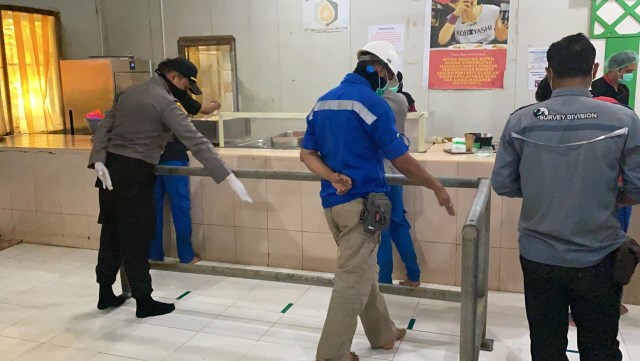 Tampak Kapolsek Obi Kabupaten Halsel, Ipda. Kris Tofel, melihat jarak di tempat antrian pengambilan makanan bagi karyawan. Foto: Istimewa