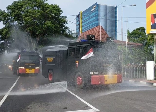 Upaya petugas kepolisian melakukan penyemprotan cairan disinfektan di sejumlah jalan utama di Palembang. (foto: istimewa)