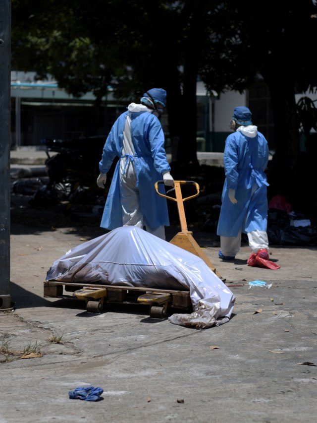 Petugas kesehatan menggunakan alat pelindung membawa jenazah di luar rumah sakit Teodoro Maldonado Carbo, Guayaquil, Ekuador. Foto: REUTERS / Vicente Gaibor del Pino