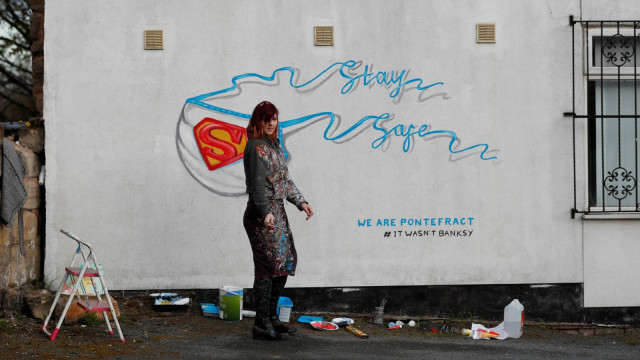 Dukungan untuk para petugas medis seorang seniman jalanan Inggris membuat sebuah mural bergambar masker berlogo Superman. Foto: REUTERS/Lee Smith