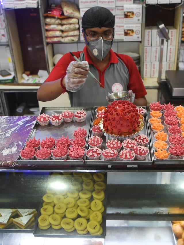 Pekerja menyelesaikan pembuatan manisan berbentuk virus corona di Kolkata, India.  Foto: AFP/Dibyangshu SARKAR