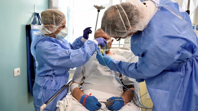 Tim medis membantu melepas alat pernafasan pasien corona sebelum video call dengan kerabat. Foto: REUTERS/Flavio Lo Scalzo