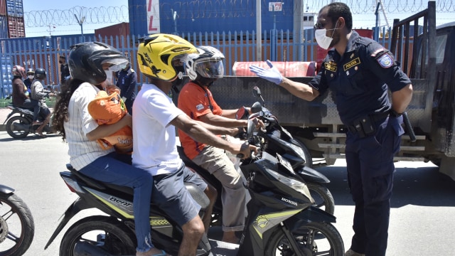 Seorang polisi Timor Leste yang mengenakan masker meminta para pengendara sepeda motor hanya satu orang per sepeda untuk cegah corona di Dili. Foto: AFP/VALENTINO DARIELL DE SOUSA