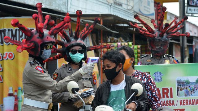 Anggota polisi lalu lintas Polres Mojokerto melakukan mengecek suhu  badan dengan memakai helm virus corona di pasar tradisional Sawahan, Jawa Timur. Foto: ANTARA FOFO/Syaiful Arif
